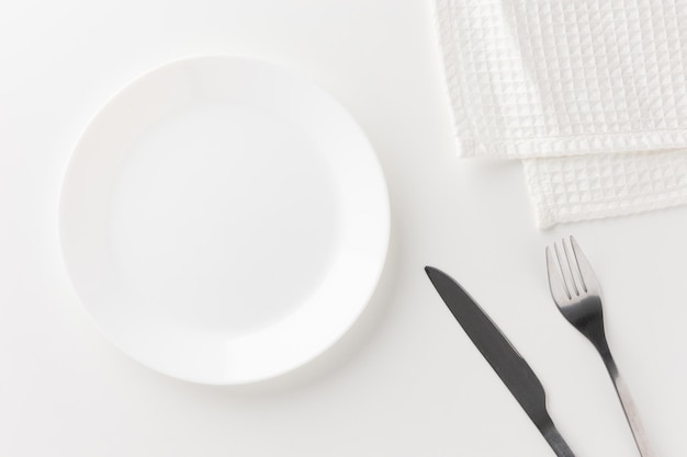 Piatti vuoti bianchi sul tavolo con coltelli, forchette e tovaglie. Pronto a mangiare