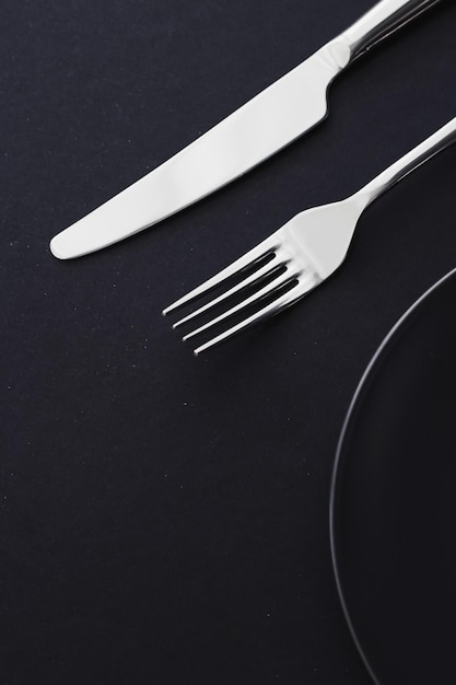 Piatti vuoti e posate su sfondo nero stoviglie premium per la cena delle vacanze design minimalista e dieta