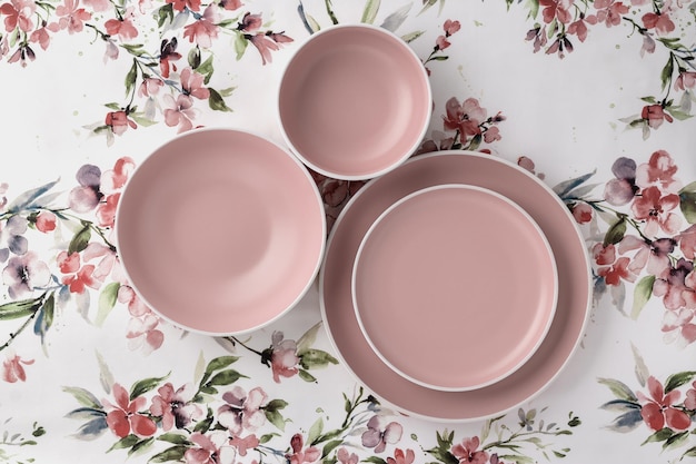 Piatti vuoti e puliti su una tovaglia bianca con vista dall'alto del tavolo con motivo floreale Design minimalista a posa piatta Stoviglie in ceramica rosa Set di stoviglie alla moda per servire e mangiare piatti Piatti beige