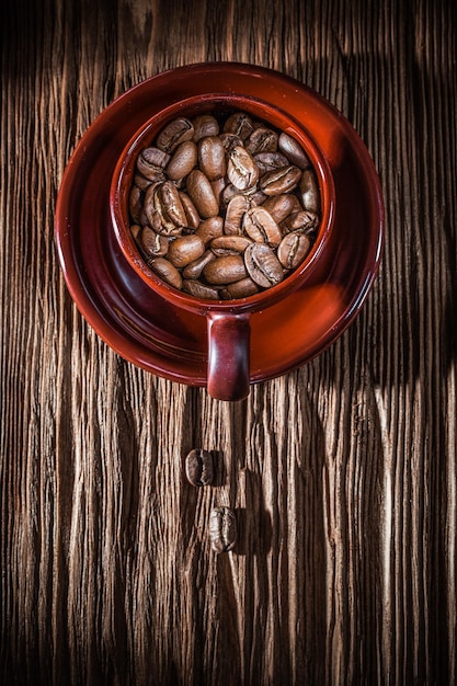 Piattino della tazza dei chicchi di caffè sulla tavola di legno dell'annata