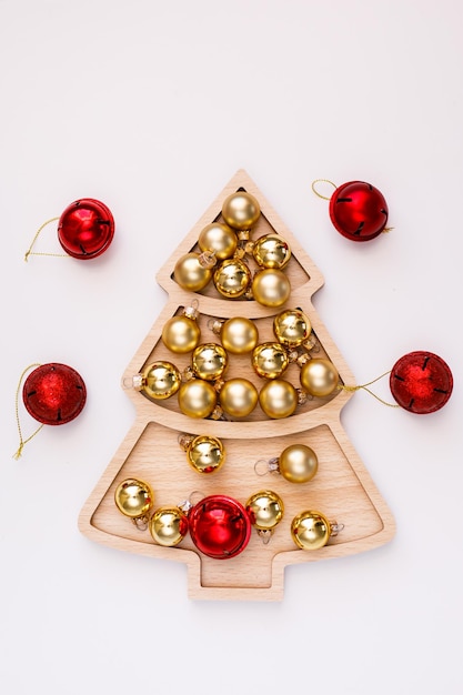 Piatto a forma di albero di Natale bianco di Capodanno su un vassoio di legno con palline d'oro e dadi con il numero 25. Concetto di Capodanno con spazio per il testo