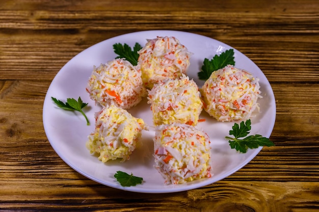 Piatto bianco con palline di formaggio di granchio su tavola di legno rustica