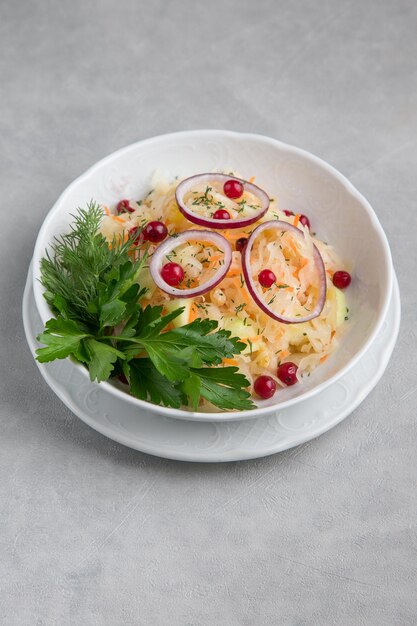 Piatto bianco con pomodoro e prezzemolo alle erbe con pomodori secchi e sfondo grigio