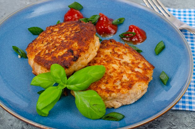 Piatto blu con due cotolette di carne macinata. Foto dello studio.