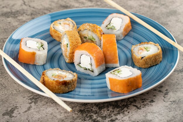 Piatto blu di Philadelphia e rotoli di sushi caldi sul tavolo.