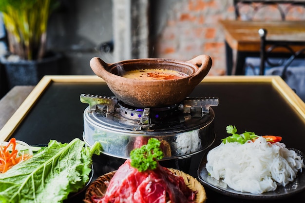 Piatto caldo piccante coreano con carne di manzo e tagliatelle su sfondo nero