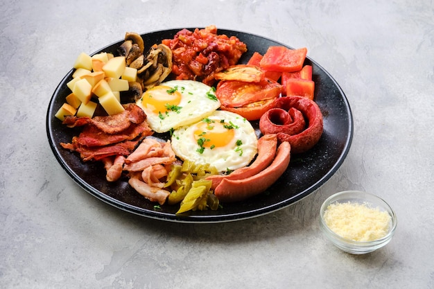 Piatto colazione. Uovo fritto, salsiccia, champignon, bacon, ragù di fagioli, prosciutto, cheddar, pomodoro e peperone