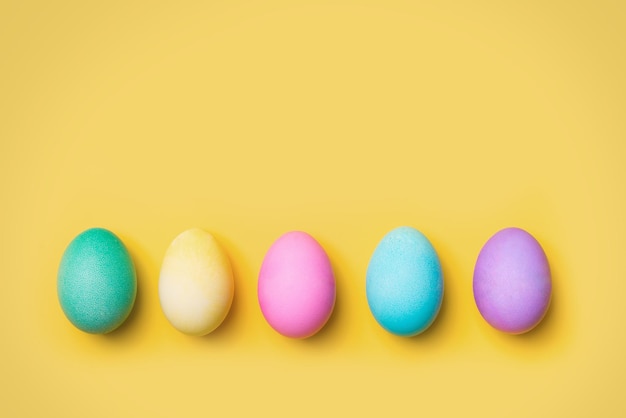 Piatto colorato di Pasqua con fila di uova e su sfondo giallo copia spazio scheda vista dall'alto