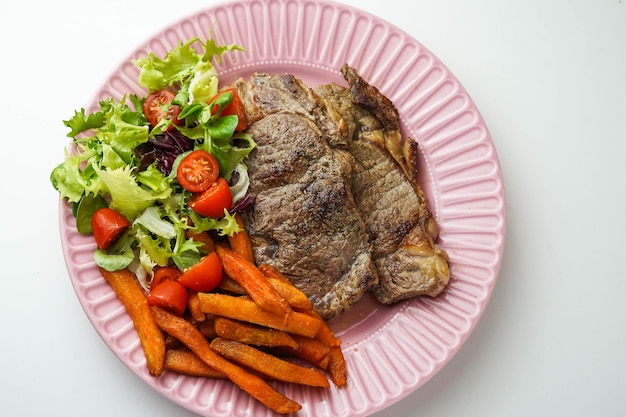 Piatto combinato di bistecca con patate dolci fritte e insalata