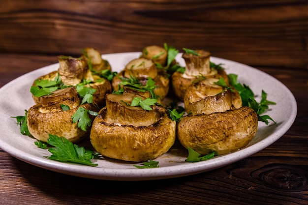 Piatto con aneto e prezzemolo champignon al forno su un tavolo di legno