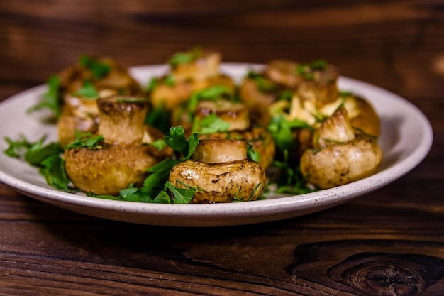 Piatto con aneto e prezzemolo champignon al forno su un tavolo di legno