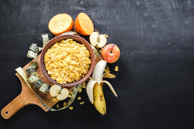 Piatto con cornflakes con frutta su fondo nero. Cibo salutare