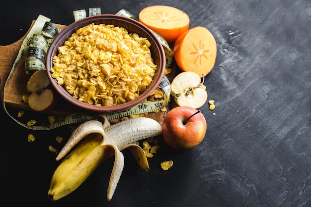 Piatto con cornflakes con frutta su fondo nero. Cibo salutare