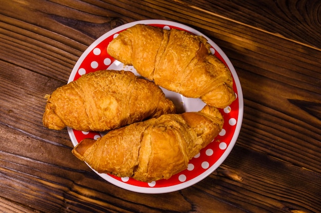 Piatto con croissant sulla tavola di legno rustica. Vista dall'alto