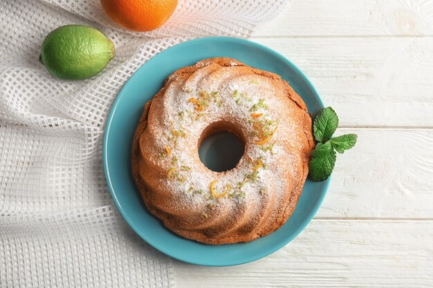 Piatto con deliziosa torta di agrumi e scorza d'arancia sul tavolo di legno