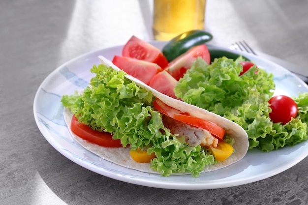 Piatto con deliziosi taco di pesce e verdure sul tavolo della cucina