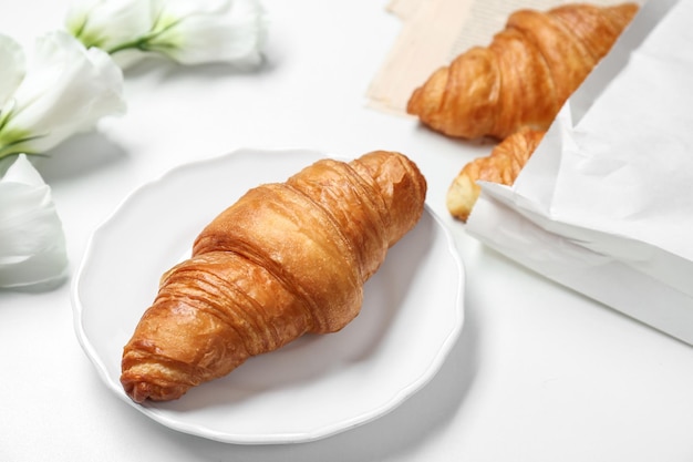 Piatto con delizioso croissant su sfondo bianco