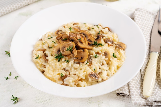 Piatto con delizioso risotto con funghi in piatto Porridge di riso con funghi e tmyne Piatto caldo cucina italiana