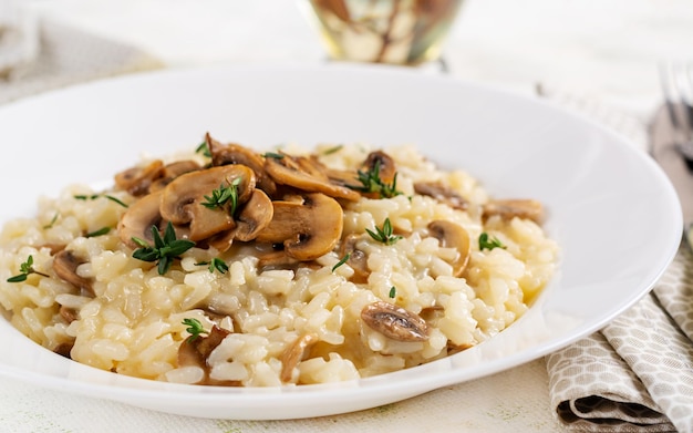 Piatto con delizioso risotto con funghi in piatto Porridge di riso con funghi e tmyne Piatto caldo cucina italiana