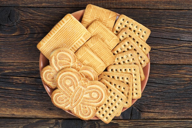 Piatto con diversi biscotti dolci su fondo di legno, vista dall'alto