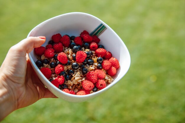 Piatto con farina d'avena e frutta fresca lamponi ribes e melone sull'erba il concetto di mangiare sano primo piano