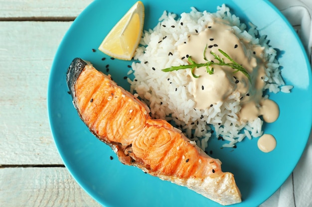 Piatto con fetta di riso al salmone e deliziosa salsa sul primo piano della tavola di legno