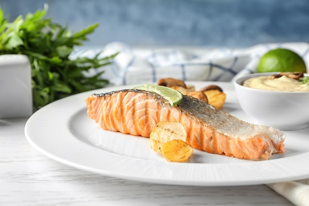 Piatto con fetta di salmone delizioso e salsa di pesce sul tavolo