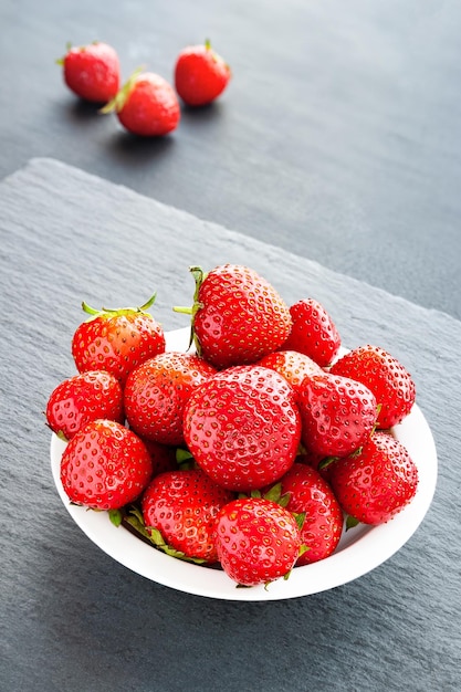 Piatto con fragole Fragole in un piatto bianco su sfondo grigio Bacche sane