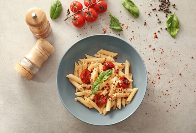 Piatto con gustose penne su tavola grigia