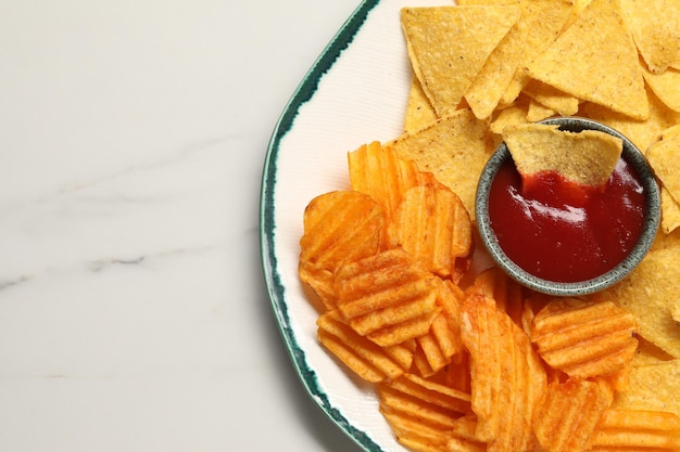 Piatto con gustoso ketchup increspato e tortilla chips sulla vista dall'alto del tavolo in marmo Spazio per il testo