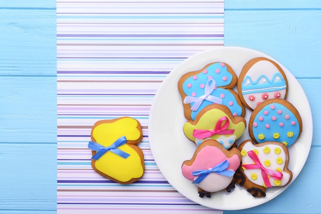 Piatto con i biscotti di Pasqua decorativi sul tovagliolo e sulla tavola di legno blu