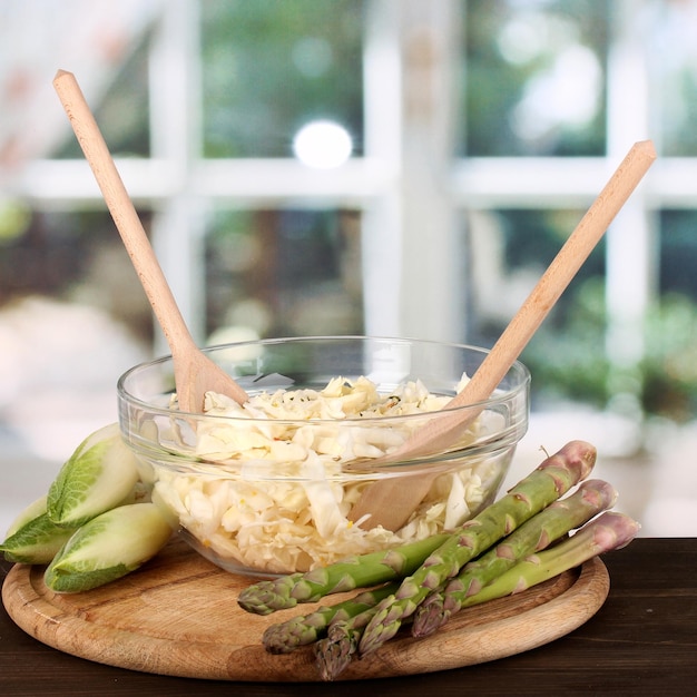 Piatto con insalata di cavolo asparagi e cicoria su tavola di legno su sfondo finestra