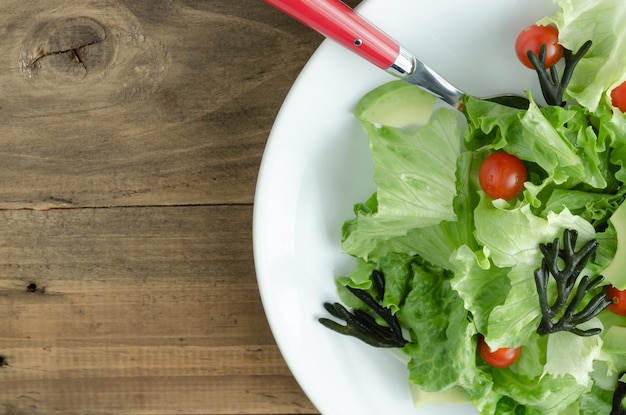 Piatto con insalata di verdure assortite su piatto bianco su sfondo di legno Copia spazio