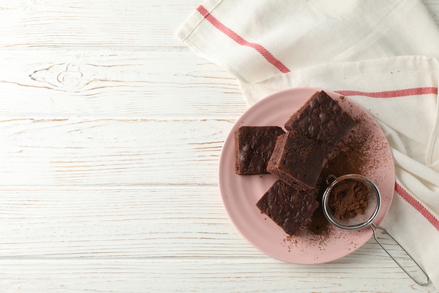 Piatto con le fette e il filtro della torta di cioccolato sulla tavola di legno con l'asciugamano