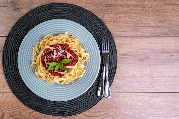 Piatto con le tagliatelle condite con salsa di pomodoro, con un bicchiere di vino rosso frizzante.