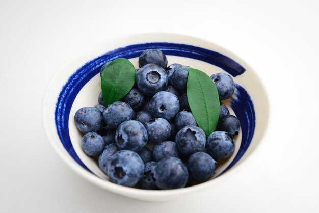 Piatto con mirtillo maturo su sfondo bianco Ciotola con mirtillo maturo Gocce d'acqua su mirtillo dolce maturo Raccolta di bacche blu e nere Immagine concettuale del cibo