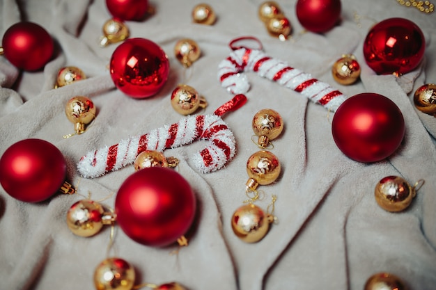 Piatto con palle di Natale rosse, palle di Natale dorate e bastoncini di zucchero di Natale sul plaid.