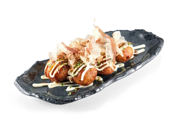 Piatto con palline di polpo di grano fritto giapponese di Takoyaki condite con fiocchi di bonito isolati su sfondo bianco