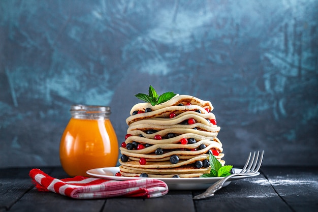 Piatto con pancake al forno fatti in casa con bacche fresche e barattolo di marmellata per una deliziosa colazione