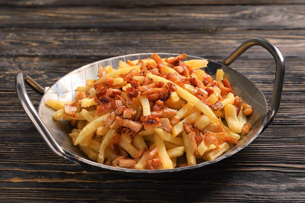 Piatto con patatine fritte e pancetta su fondo di legno