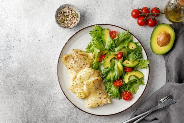 Piatto con pesce bianco al forno Insalata di frillis pomodori avocado e semi Cena di pesce salutare Vista dall'alto