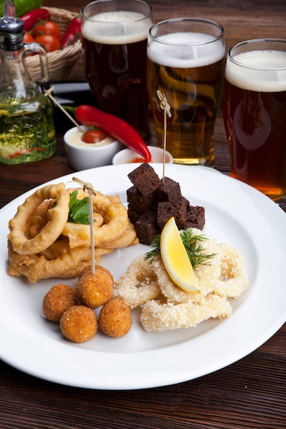 piatto con snack alla birra crostini fritti calamari cipolle e salse