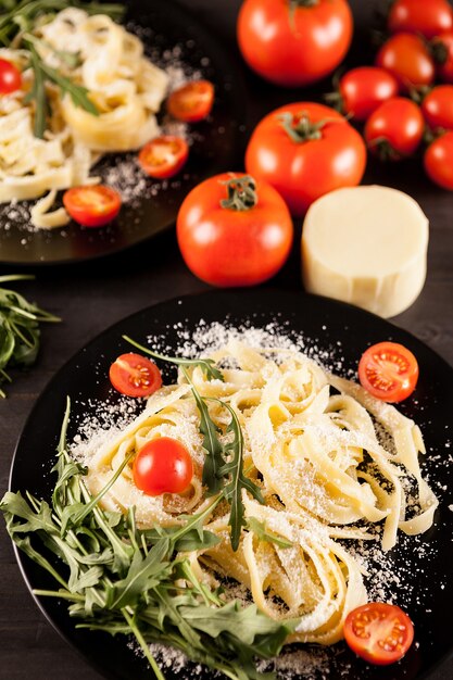 Piatto con tagliatelle, pomodorini e verde su tavola di legno