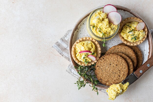 Piatto con tartellette crackers multicereali con patè di uova o insalata servita con ravanelli e timo