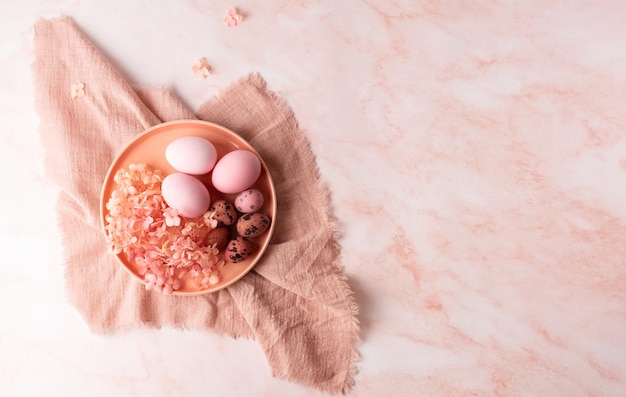 Piatto con uova rosa e fiori di ortensia su fondo pasquale in marmo