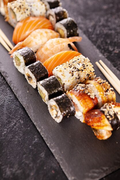 Piatto con varietà di sushi su uno sfondo di pietra scura. Cucina sana
