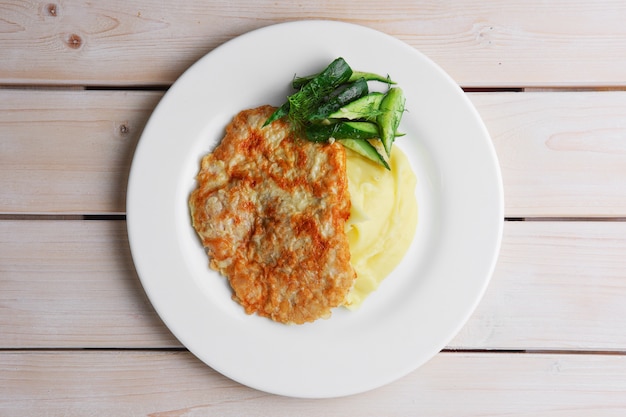 Piatto con vista dall&#39;alto di piatto con maiale tritato in impanatura e purè di patate decorato con cetriolo tritato di maiale in impanatura e purè di patate decorato con cetriolo