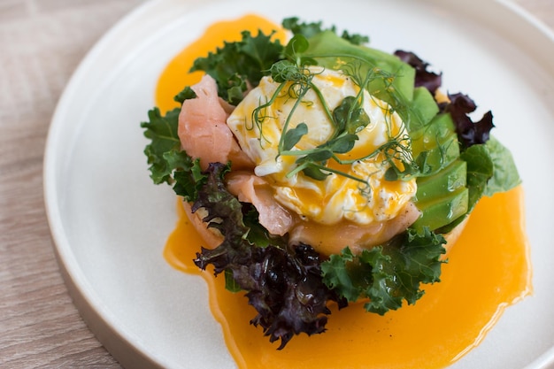 Piatto da ristorante Brioche con uovo in camicia con salmone e avocado Delizioso pane con verdure