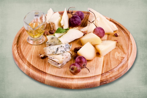 Piatto del ristorante composto da formaggio, uva e salsa su piatto di legno