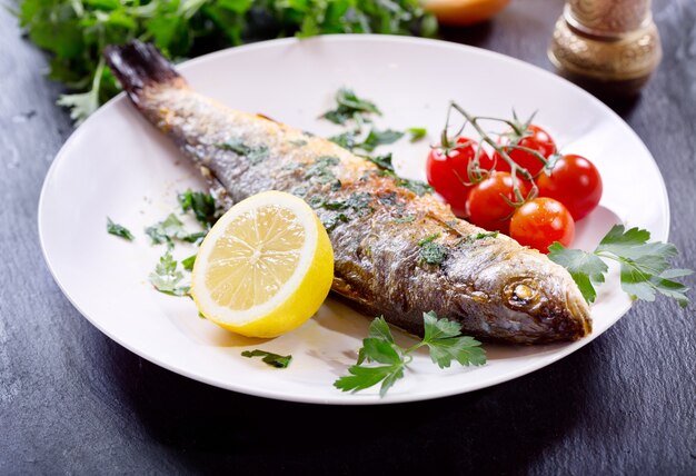 Piatto di branzino al forno su scuro, vista dall'alto